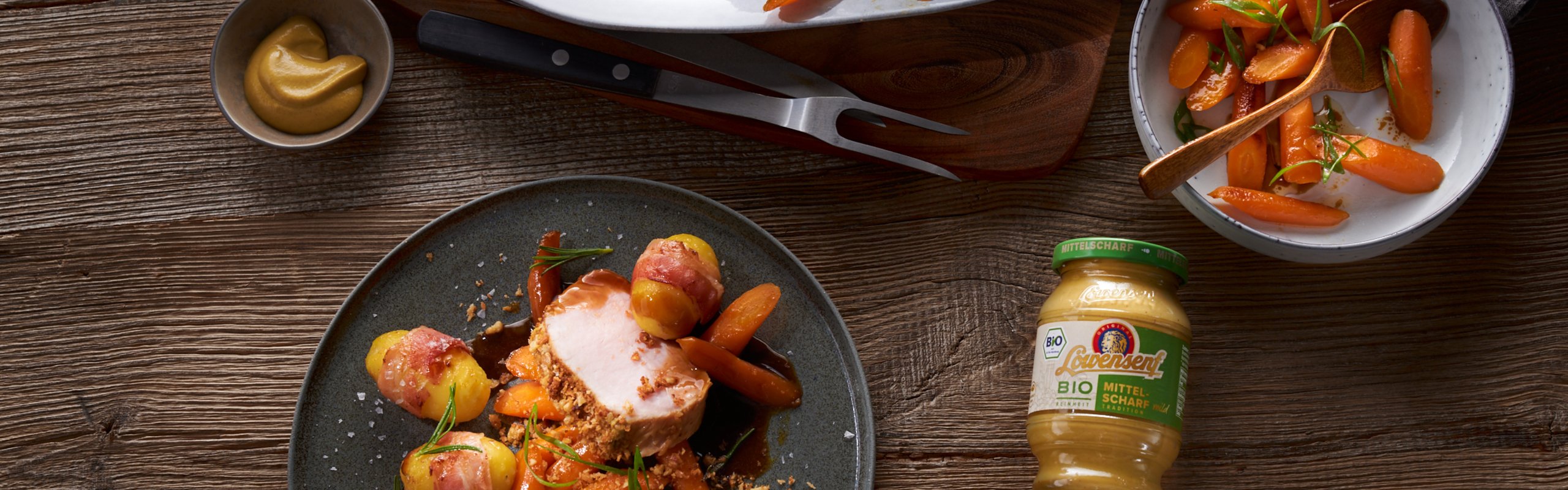 Rosa gebratener Schweinebraten mit Senf-Walnusskruste in Rosmarinsauce auf Honigmöhren mit Löwensenf Bio Mittelscharfer Senf